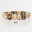 A beaded stretch bracelet featuring faceted iridescent champagne and amber-colored stones set in cream and dark brown bezels, shown on a reflective white surface with the text '#02' below.