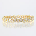 A yellow gold eternity-style band bracelet featuring a row of teardrop-shaped clear gemstones in bezel settings, shown on a clean white background with a soft reflection below.