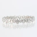 A silver-toned stretch bracelet featuring a row of teardrop-shaped clear gemstones in a bezel setting, displayed on a reflective white surface.