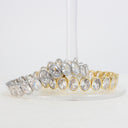Two stretch bracelets with oval clear stones in silver and gold settings, displayed on a clear stand against a white background.