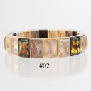 A rectangular-link bangle bracelet with iridescent opalescent crystals in a gold-tone setting, shown on a reflective white surface. The center of the image has a text overlay reading '#02'.