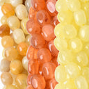 Close-up of three strands of glossy, translucent oval beads in yellow, orange, and cream colors.
